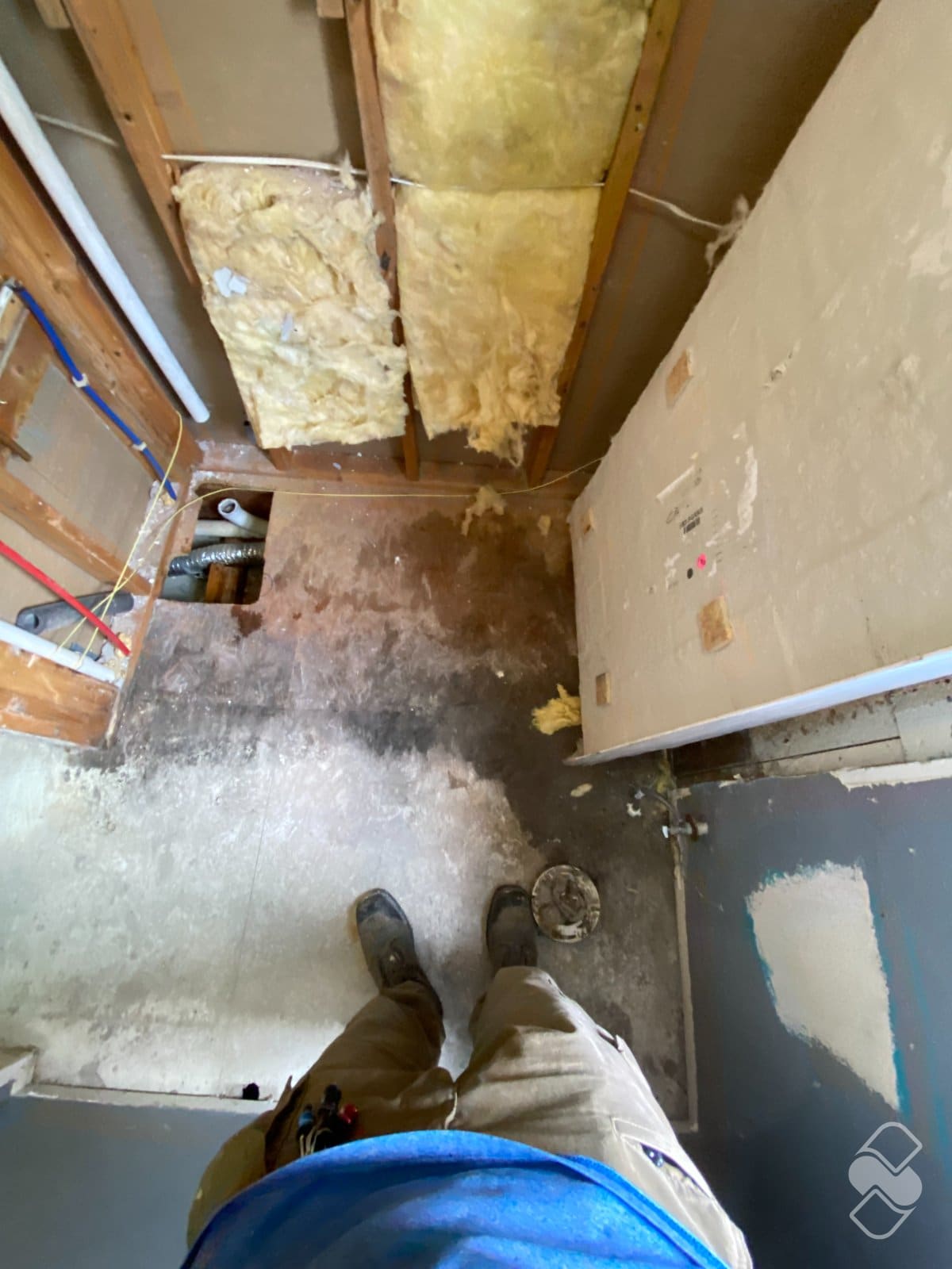 Bathroom stripped to the subfloor with the old plumbing exposed during a remodel