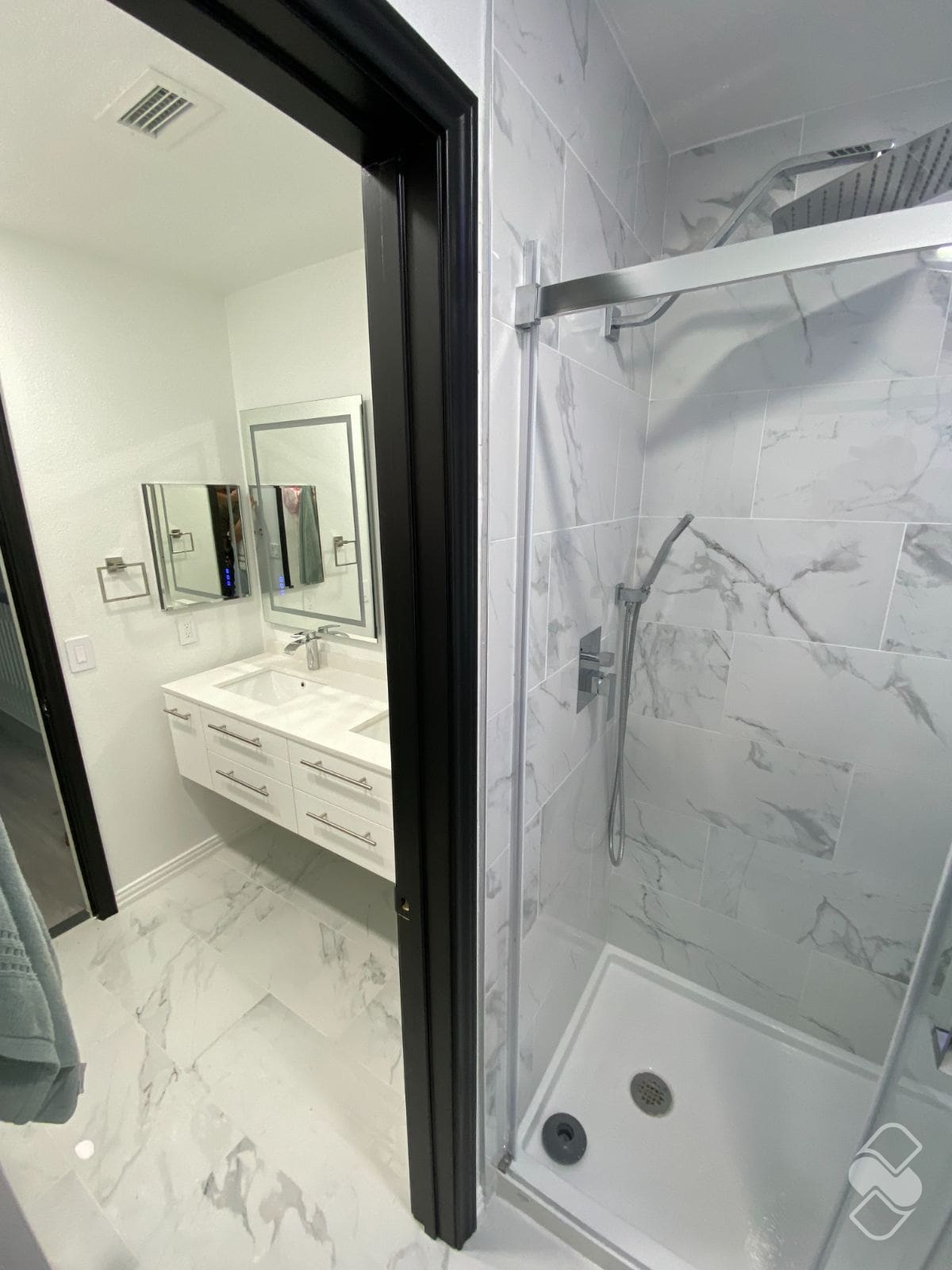 A finished bathroom remodel with a marble tile walk-in shower and a double vanity