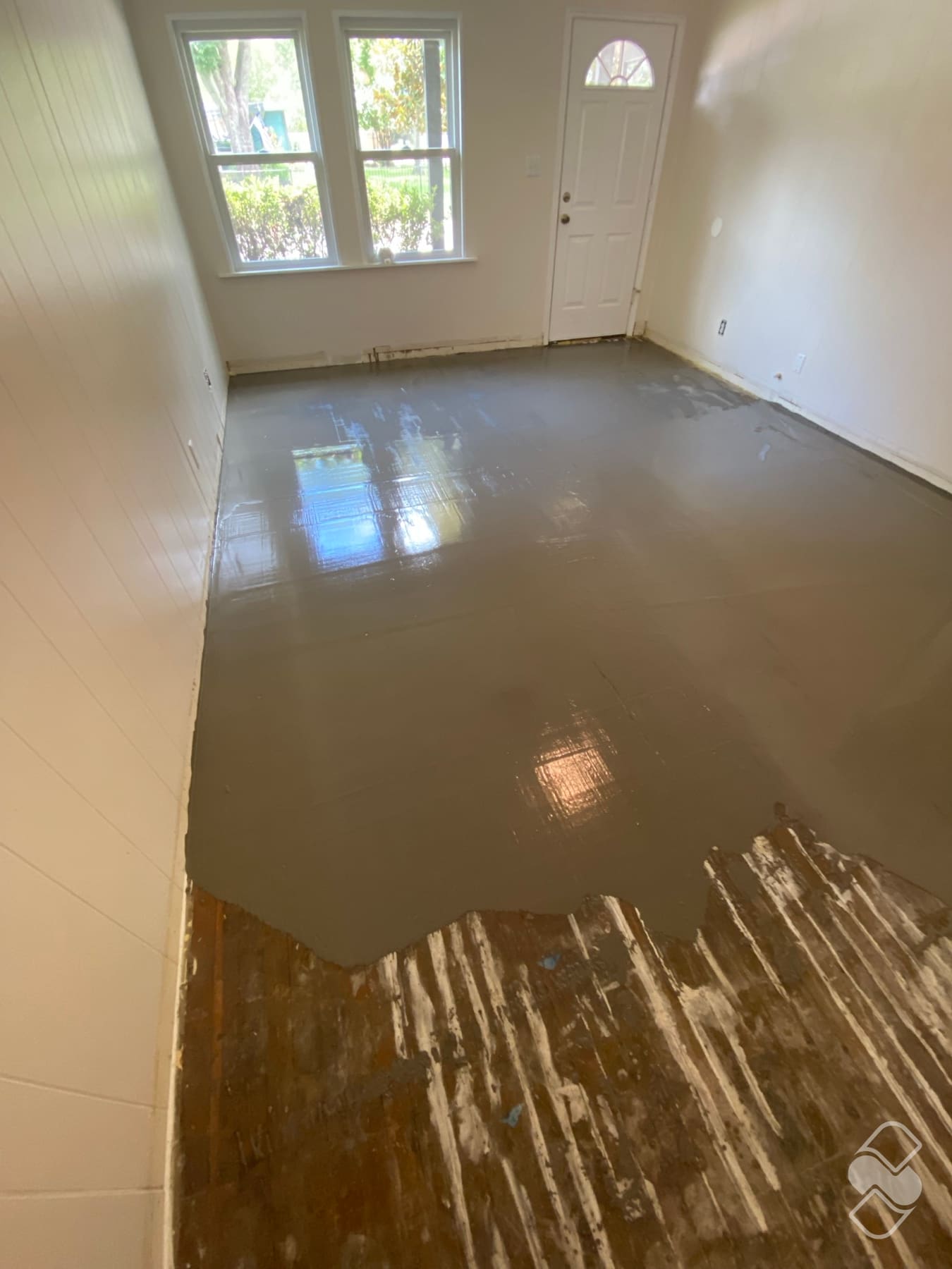 Freshly poured self leveling compound spread flat across a subfloor before new flooring installation