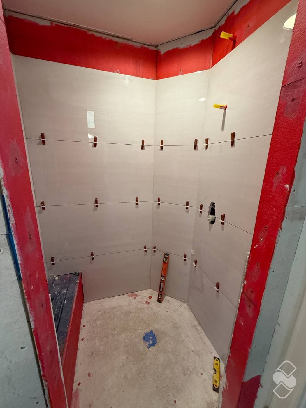 Shower walls covered in waterproofing membrane with large format tile being installed over them