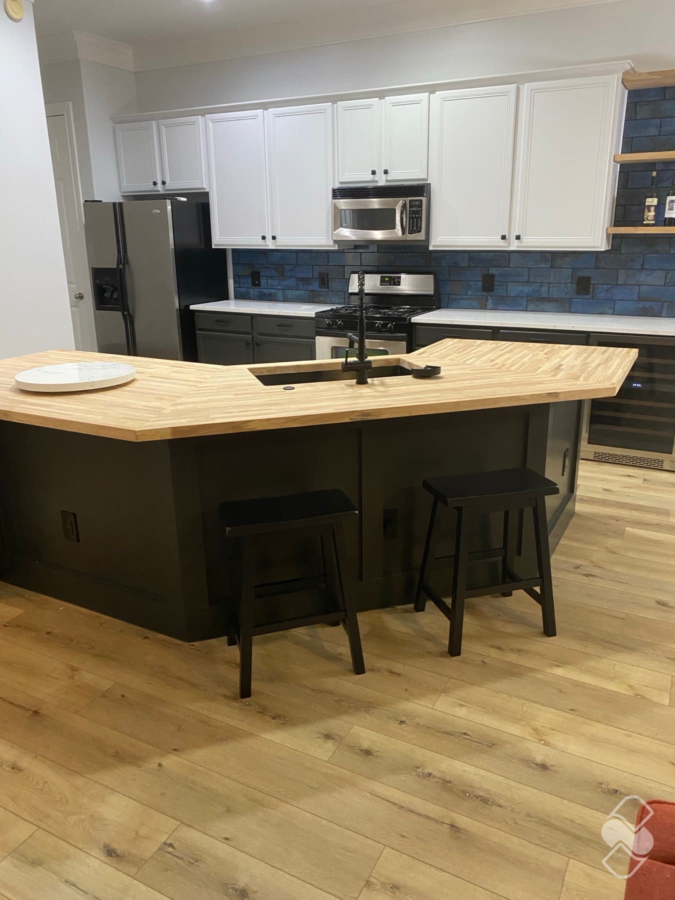 A finished kitchen remodel in Katy with a butcher-block island, tile backsplash and wood-look floors